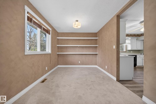 Neutral-toned room featuring a single window with brown blinds, built-in shelving, carpet flooring, and a flush-mount ceiling light - 1767 61 Street, Edmonton, AB - Indoor Photo Showing Other Room