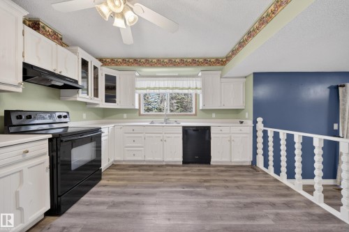 Spacious kitchen featuring white cabinetry, a window over the sink, and wood-finish flooring - 1767 61 Street, Edmonton, AB - Indoor Photo Showing Kitchen