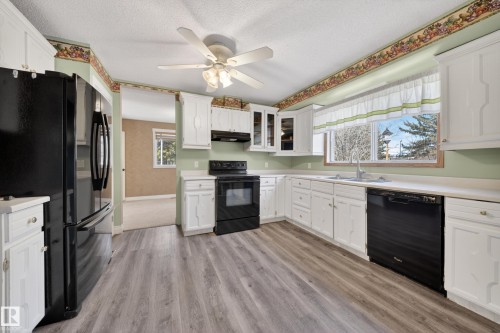 Kitchen featuring wood-finish flooring, white cabinetry, a double basin sink, and black appliances - 1767 61 Street, Edmonton, AB - Indoor Photo Showing Kitchen