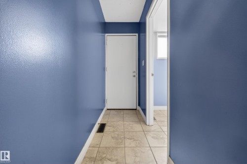 Hallway featuring tiled flooring, white baseboards, and a white door with silver-toned hardware - 1767 61 Street, Edmonton, AB - Indoor Photo Showing Other Room