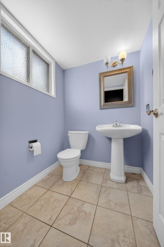 Powder room featuring a pedestal sink, white toilet, and beige tile flooring - 1767 61 Street, Edmonton, AB - Indoor Photo Showing Bathroom