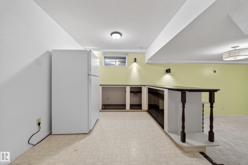 Lower level featuring a built-in bar, white refrigerator, and a combination of resilient flooring and carpeting - 1767 61 Street, Edmonton, AB - Indoor