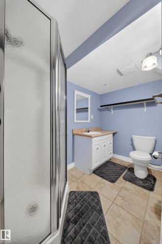 Bathroom featuring a shower enclosure with textured glass, a white vanity with a light wood-finish countertop, a single basin sink, and tile flooring - 1767 61 Street, Edmonton, AB - Indoor Photo Showing Bathroom