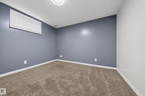 Carpeted room featuring a light fixture, a window with horizontal blinds, and a combination of blue and white painted walls - 1767 61 Street, Edmonton, AB - Indoor Photo Showing Other Room
