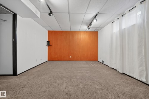 Spacious room featuring neutral carpeting and a distinct orange accent wall - 1767 61 Street, Edmonton, AB - Indoor Photo Showing Other Room