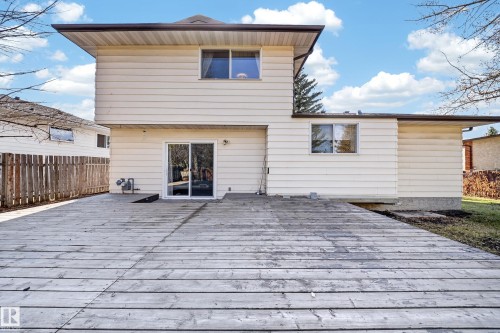 Expansive wood deck with a ground-level entrance, featuring a sliding glass door and multiple windows on the rear facade - 1767 61 Street, Edmonton, AB - Outdoor With Exterior
