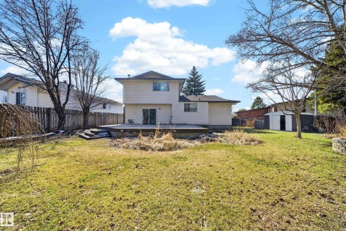 Expansive backyard featuring a large grass area, a multi-level wood deck, a rear sliding glass door, and a detached storage shed - 1767 61 Street, Edmonton, AB - Outdoor