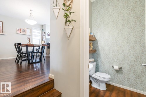 Powder room featuring patterned wallpaper and wood-finish flooring - 5127 1A Avenue, Edmonton, AB - Indoor Photo Showing Bathroom