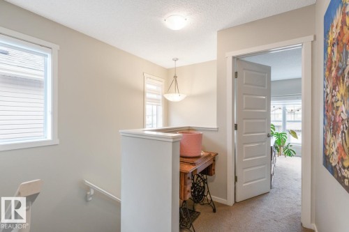 Upper-level landing featuring neutral paint, carpet flooring, a multi-pane window, and a paneled interior door - 5127 1A Avenue, Edmonton, AB - Indoor Photo Showing Other Room