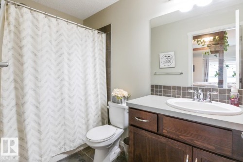 Bathroom vanity with a composite countertop, undermount sink, and wood-finish cabinetry - 5127 1A Avenue, Edmonton, AB - Indoor Photo Showing Bathroom