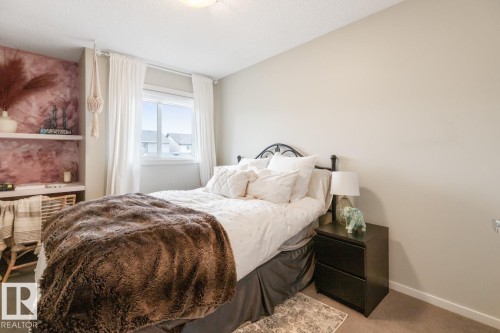 Bedroom featuring a window with white trim, built-in shelving with a unique pink finish, and neutral wall paint - 5127 1A Avenue, Edmonton, AB - Indoor Photo Showing Bedroom