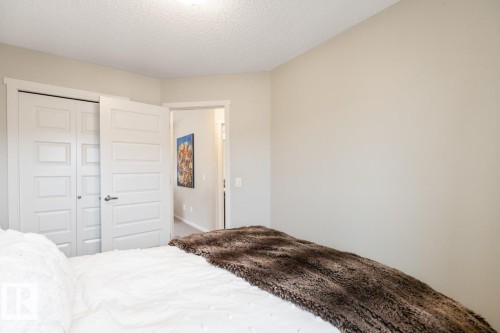 Light-colored walls with white trim, white paneled doors, and a textured ceiling - 5127 1A Avenue, Edmonton, AB - Indoor Photo Showing Bedroom
