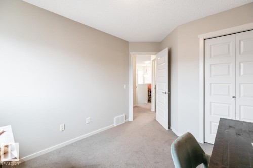 Room featuring neutral wall tones, textured carpet flooring, white baseboards, and a paneled bifold closet door - 5127 1A Avenue, Edmonton, AB - Indoor