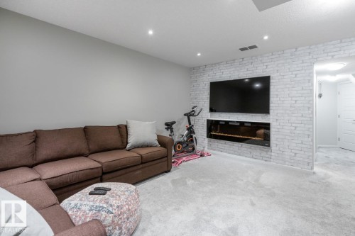 Living area featuring light gray carpet flooring - 5127 1A Avenue, Edmonton, AB - Indoor Photo Showing Living Room With Fireplace