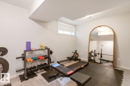 Versatile room featuring light gray wall paint, carpeting, a rectangular window with a roller shade, and ceiling-mounted lighting - 5127 1A Avenue, Edmonton, AB - Indoor Photo Showing Gym Room