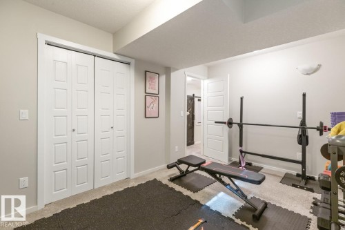 Finished room with soft gray wall color, neutral carpet flooring, a white bi-fold closet, and a white interior door - 5127 1A Avenue, Edmonton, AB - Indoor Photo Showing Gym Room