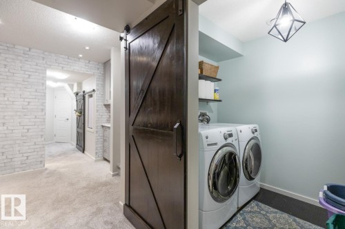Dark wood-finish sliding barn door entryway leading to a laundry area with stacked appliances - 5127 1A Avenue, Edmonton, AB - Indoor Photo Showing Laundry Room