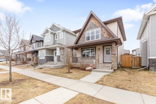 Craftsman-style home featuring a covered front porch with stone accents, horizontal siding, and decorative shingle details on the gable - 5127 1A Avenue, Edmonton, AB - Outdoor With Deck Patio Veranda With Facade