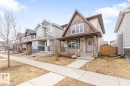 Craftsman-style home featuring a covered front porch with stone accents, horizontal siding, and decorative shingle details on the gable - 5127 1A Avenue, Edmonton, AB  - Outdoor With Deck Patio Veranda With Facade 