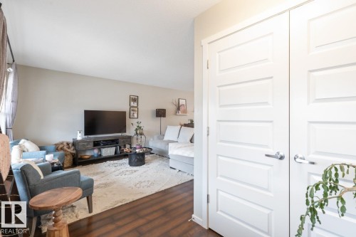 Living area featuring wood-finish flooring, light-toned walls, and a large central rug - 5127 1A Avenue, Edmonton, AB - Indoor