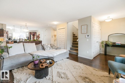 Open-concept living area featuring wood-finish flooring, a contemporary staircase with carpeted treads, and a built-in kitchen pass-through - 5127 1A Avenue, Edmonton, AB - Indoor Photo Showing Living Room