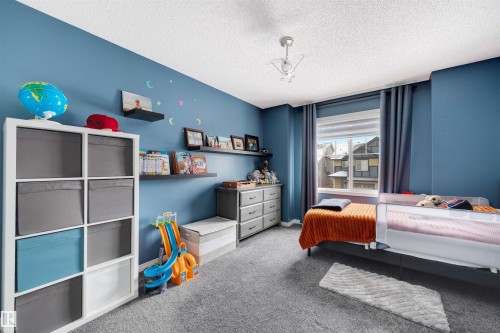 Carpeted room featuring a window with blinds, a ceiling-mounted light fixture, and built-in floating shelves - 2504 Coughlan Road, Edmonton, AB - Indoor Photo Showing Bedroom