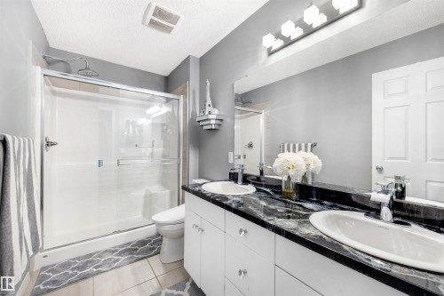 Bathroom featuring a dual vanity with white cabinetry and dark, veined countertops - 2504 Coughlan Road, Edmonton, AB - Indoor Photo Showing Bathroom