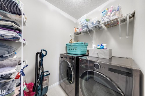 Dedicated laundry area featuring a front-loading washer and dryer, wire shelving for organization, and light-toned walls - 2504 Coughlan Road, Edmonton, AB - Indoor Photo Showing Laundry Room
