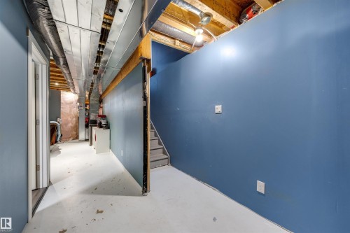 Unfinished lower level featuring blue painted walls, exposed ceiling joists, and a partial staircase - 2504 Coughlan Road, Edmonton, AB - Indoor