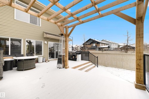 Spacious rear patio with wood pergola, multiple large windows, sliding glass patio doors, built-in steps, and a privacy fence - 2504 Coughlan Road, Edmonton, AB - Outdoor