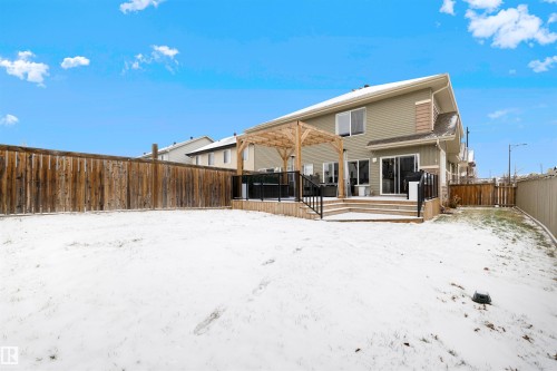 Spacious fenced backyard featuring a multi-level wood deck, an open pergola structure, and sliding glass patio doors - 2504 Coughlan Road, Edmonton, AB - Outdoor