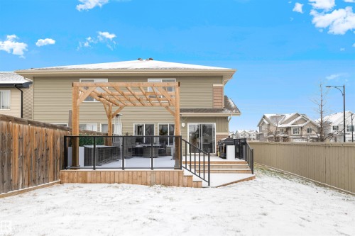 Rear exterior featuring a spacious wood deck with glass panel railing, a wood pergola, and sliding patio doors - 2504 Coughlan Road, Edmonton, AB - Outdoor With Exterior