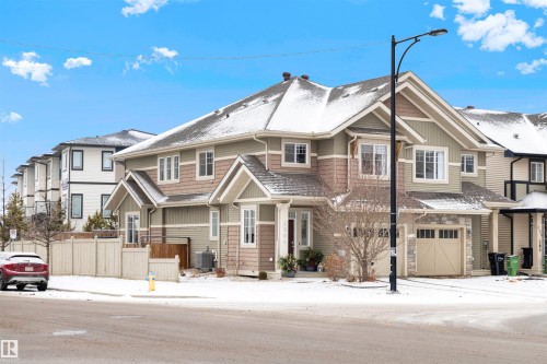 Two-story exterior featuring multi-toned siding, a peaked roofline, an attached garage with a carriage-style door, and multiple windows - 2504 Coughlan Road, Edmonton, AB - Outdoor With Facade