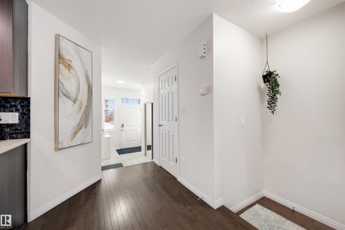 Inviting entryway featuring dark wood-finish flooring, white trim, a white entry door with frosted glass inserts, and a closet with a paneled door - 2504 Coughlan Road, Edmonton, AB - Indoor Photo Showing Other Room