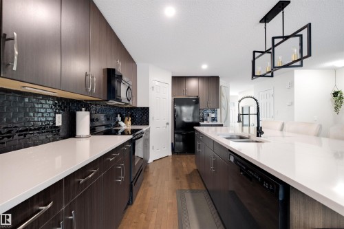 Gourmet kitchen featuring dark wood-finish cabinetry, white countertops, and a black subway tile backsplash - 2504 Coughlan Road, Edmonton, AB - Indoor Photo Showing Kitchen With Double Sink With Upgraded Kitchen