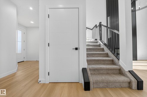 Contemporary staircase with carpeted treads and black metal balusters - 3285 Chernowski Way, Edmonton, AB - Indoor Photo Showing Other Room