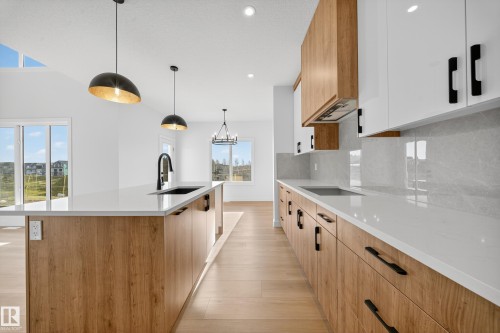 Modern kitchen featuring wood-finish lower cabinetry, white upper cabinetry, and light quartz countertops - 3285 Chernowski Way, Edmonton, AB - Indoor Photo Showing Kitchen With Upgraded Kitchen