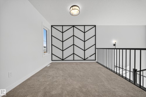 Carpeted loft area featuring a decorative geometric wall panel, a single window, an a contemporary ceiling light fixture - 3285 Chernowski Way, Edmonton, AB - Indoor Photo Showing Other Room