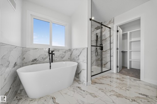 Freestanding soaking tub with a floor-mounted matte black faucet - 3285 Chernowski Way, Edmonton, AB - Indoor Photo Showing Bathroom