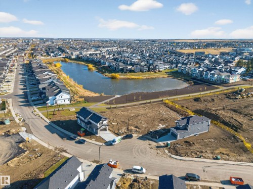 Aerial perspective showcasing a developing neighborhood with a central pond feature - 3285 Chernowski Way, Edmonton, AB - Outdoor With Body Of Water With View