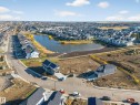 Aerial perspective showcasing a developing neighborhood with a central pond feature - 3285 Chernowski Way, Edmonton, AB  - Outdoor With Body Of Water With View 
