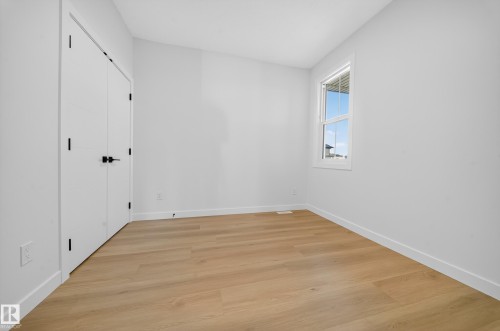 Bright room with wood-finish flooring, white walls, and a white-framed window - 3285 Chernowski Way, Edmonton, AB - Indoor Photo Showing Other Room