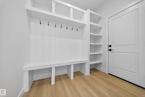 Built-in white storage unit featuring a bench, coat hooks, open shelving, and upper compartments - 3285 Chernowski Way, Edmonton, AB - Indoor