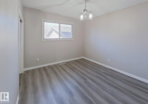 Room featuring wood-finish flooring, neutral wall paint, white trim, and a window with white casing - 9624 75 Street, Edmonton, AB - Indoor Photo Showing Other Room