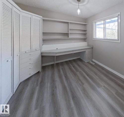 Built-in desk with shelving and integrated cabinetry featuring louvered doors - 9624 75 Street, Edmonton, AB - Indoor Photo Showing Other Room