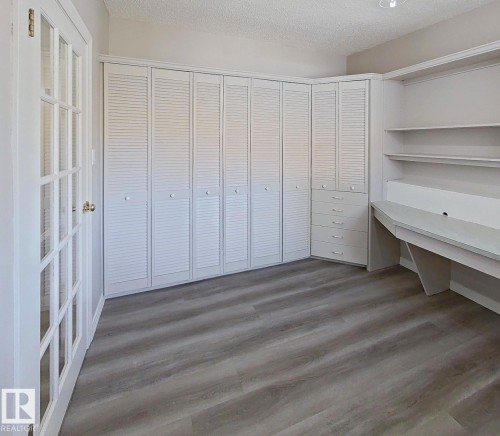 Room featuring wood-finish flooring and a built-in desk with shelving - 9624 75 Street, Edmonton, AB - Indoor Photo Showing Other Room