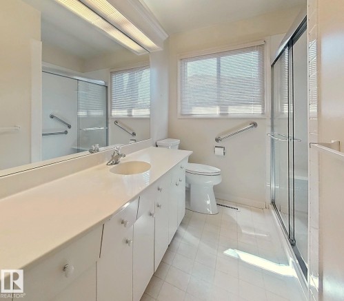 Full-length vanity with integrated sink, expansive mirror, and upper fluorescent lighting - 9624 75 Street, Edmonton, AB - Indoor Photo Showing Bathroom