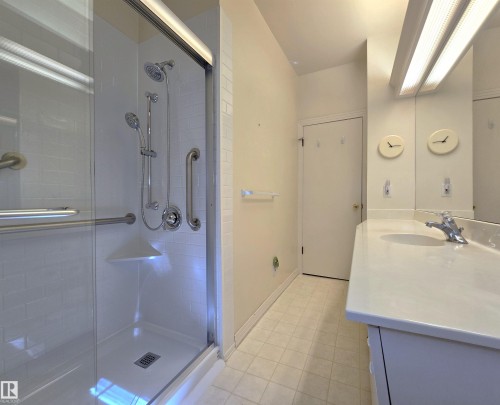 Spacious shower enclosure featuring a sliding glass door, multiple shower heads, and an integrated corner seat - 9624 75 Street, Edmonton, AB - Indoor Photo Showing Bathroom
