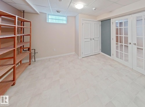 Spacious room with light-toned rectangular floor tiles, drop ceiling, and recessed lighting - 9624 75 Street, Edmonton, AB - Indoor