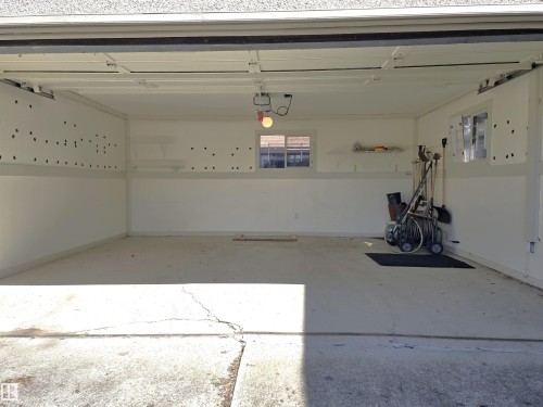 Spacious garage interior featuring concrete flooring, white painted walls, and built-in shelving - 9624 75 Street, Edmonton, AB - Indoor Photo Showing Garage